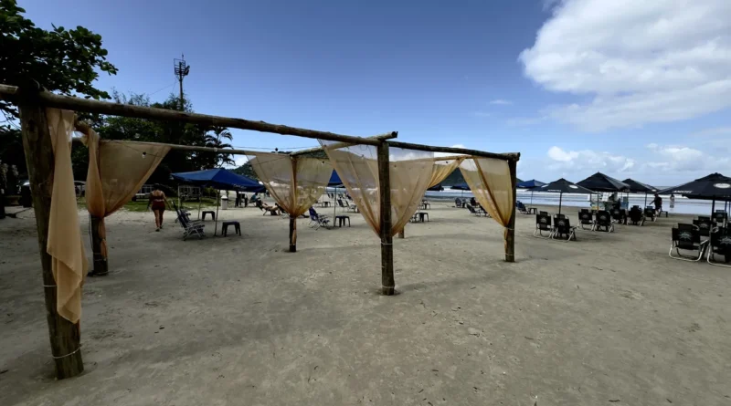 Estruturas de apoio com cobertura e cadeiras na areia da Praia do Indaiá em Bertioga.